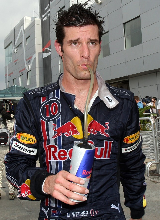Марк Уэббер идет по паддоку и пьет из банки Red Bull