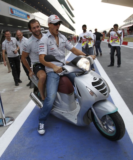 Михаэль Шумахер на мопеде с механиком покидает пит-лейн на Гран-при Индии 2011