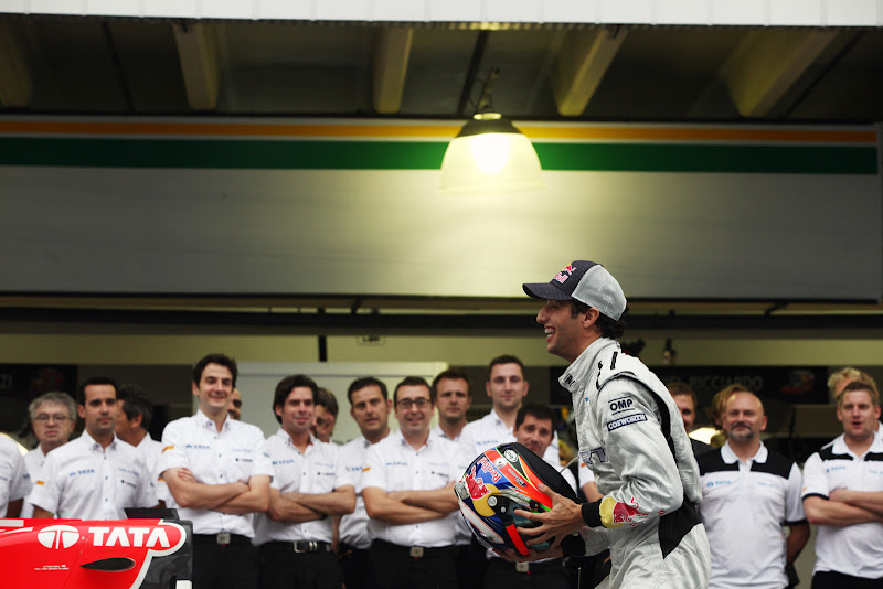 Даниэль Риккардо ловит свой шлем перед своими механиками HRT на Гран-при Бразилии 2011