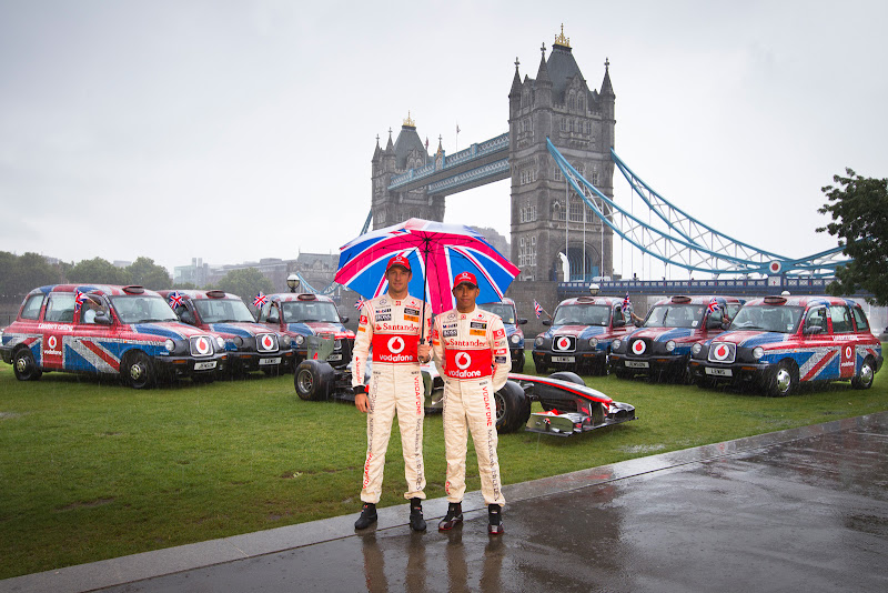 Дженсон Баттон и Льюис Хэмилтон под зонтиком в Лондоне на фоне Тауэрского моста перед Гран-при Великобритании 2011 на мероприятии Vodafone