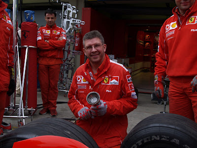 Росс Браун отрабатывает технику замены резины на Ferrari во время тренировки пит-стопов на Гран-при Бразилии 2004