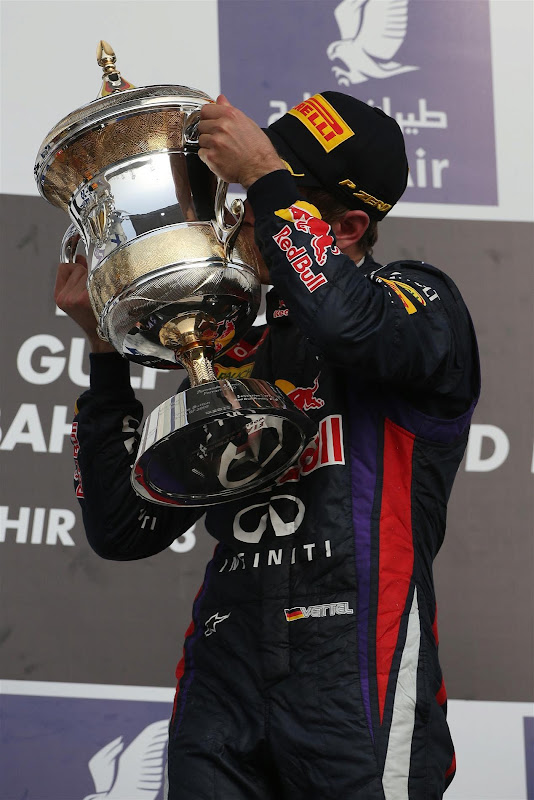 Себастьян Феттель целует кубок на подиуме Гран-при Бахрейна 2013