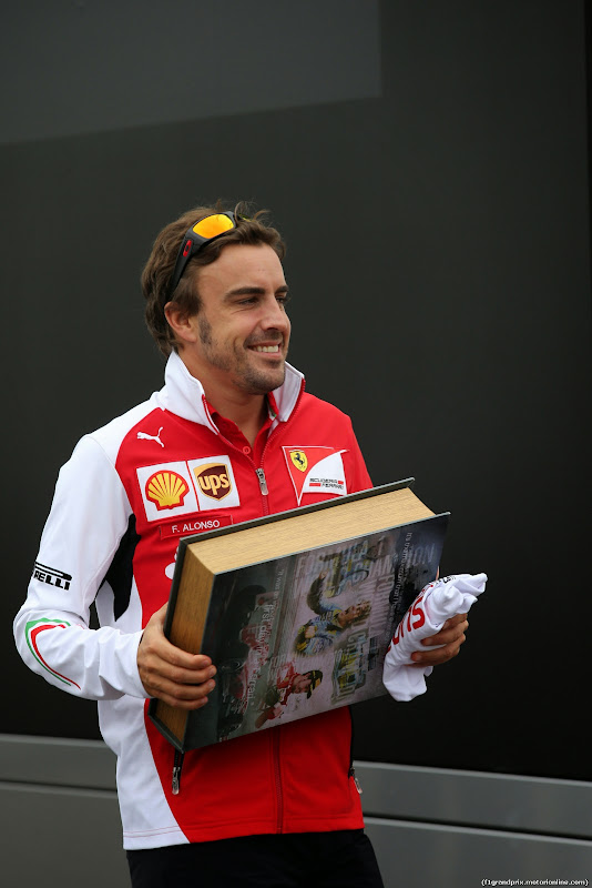 Фернандо Алонсо несет здоровенную книгу по паддоку Монцы на Гран-при Италии 2014
