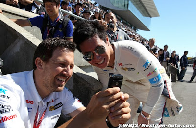 механик показывает что-то смешное на телефоне Камуи Кобаяши на Гран-при Японии 2011