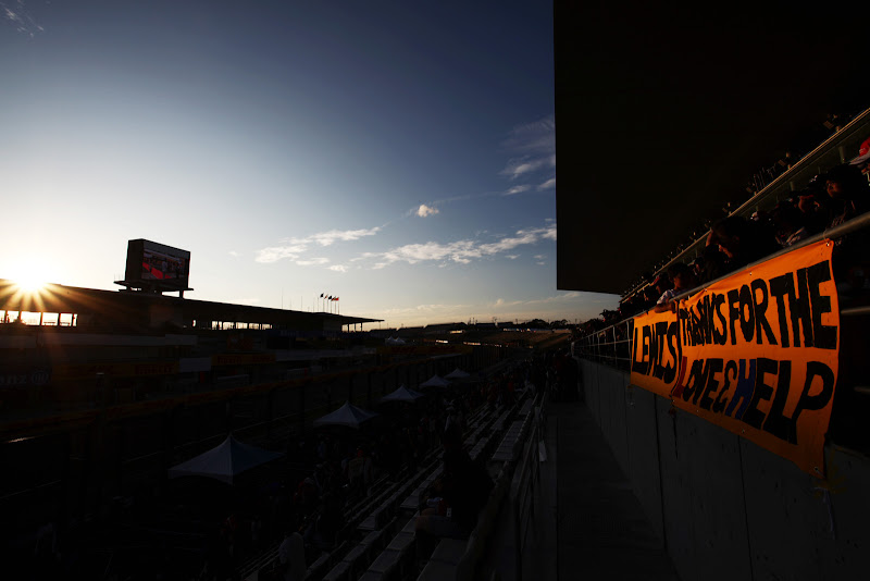 плакат болельщиков Льюиса Хэмилтона под заходящим солнцем трассы Сузука на Гран-при Японии 2011