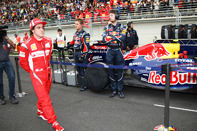 Фернандо Алонсо проходит мимо болида Red Bull на стартовой решетке Гран-при Кореи 2011