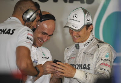 Нико Росберг показывает что-то смешное на телефоне своим механикам на Гран-при Китая 2012