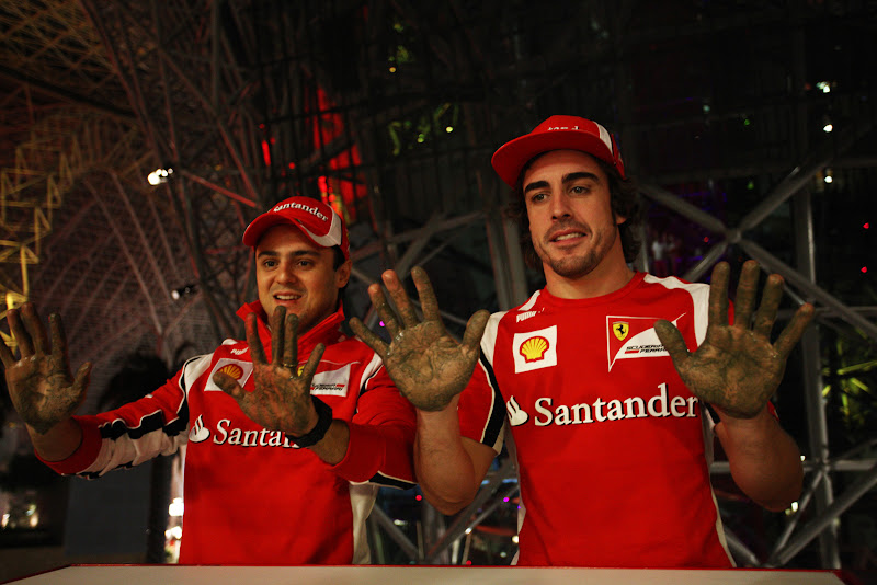 Фелипе Масса и Фернандо Алонсо показывают руки после отпечаток рук в Ferrari World на Гран-при Абу-Даби 2011