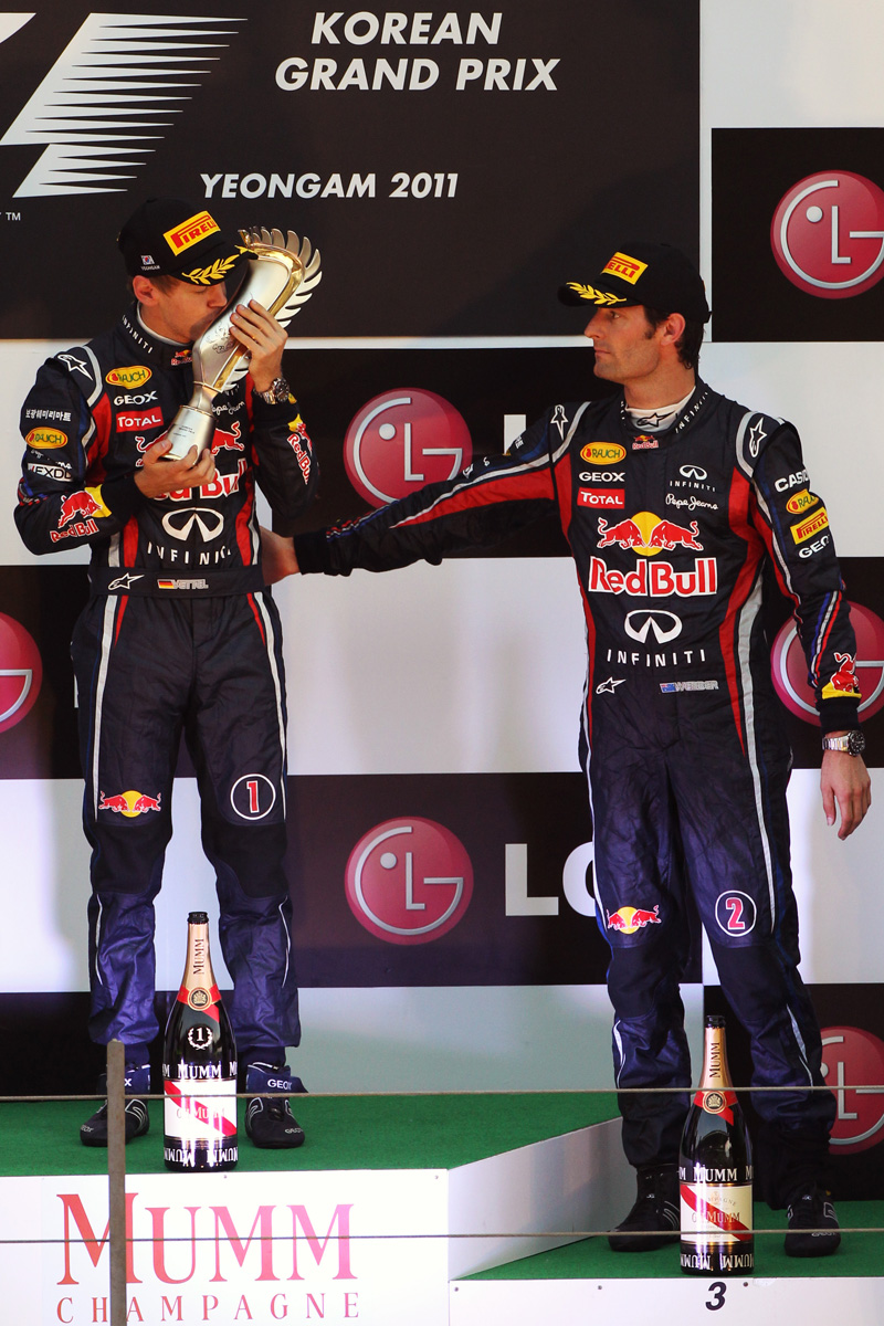 Себастьян Феттель с трофеем и Марк Уэббер вытирает руку об напарника на подиуме Гран-при Кореи 2011