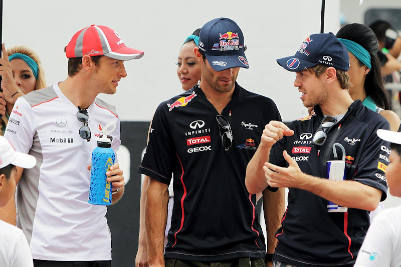 Себастьян Феттель показывает что-то Дженсону Баттону и Марку Уэбберу на параде пилотов Гран-при Малайзии 2012