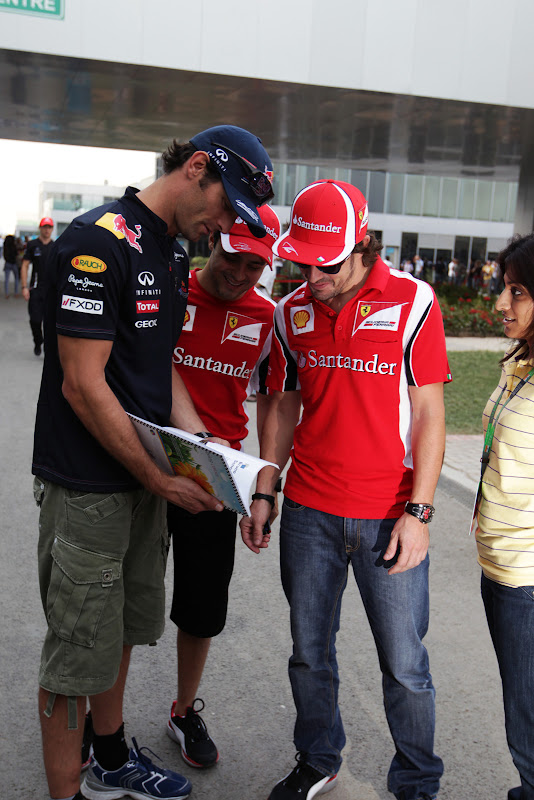 Марк Уэббер показывает книжку Фелипе Массе и Фернандо Алонсо на Гран-при Индии 2011