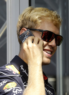 блондин Себастьян Феттель разговаривает по телефону на Гран-при Бельгии 2013
