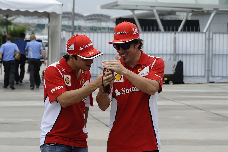 Фернандо Алонсо показывает что-то забавное на телефоне Фелипе Массе на Гран-при Малайзии 2012