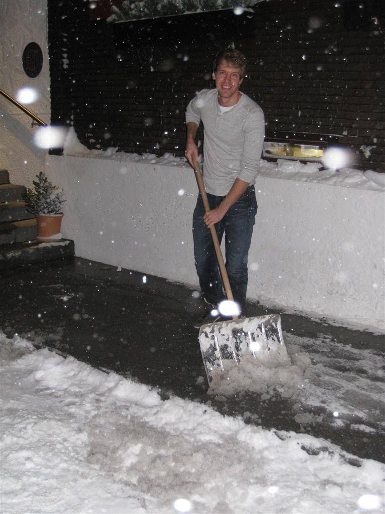 улыбающийся Себастьян Феттель убирает снег перед отелем Rote Wand 30 декабря 2011