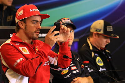 Фернандо Алонсо фотографирует что-то на телефон на пресс-конференции в четверг на Гран-при США 2012