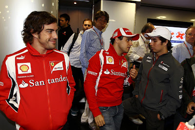 улыбающийся Фернандо Алонсо наблюдает за разговором Фелипе Массы и Серхио Переса на Гран-при Венгрии 2011