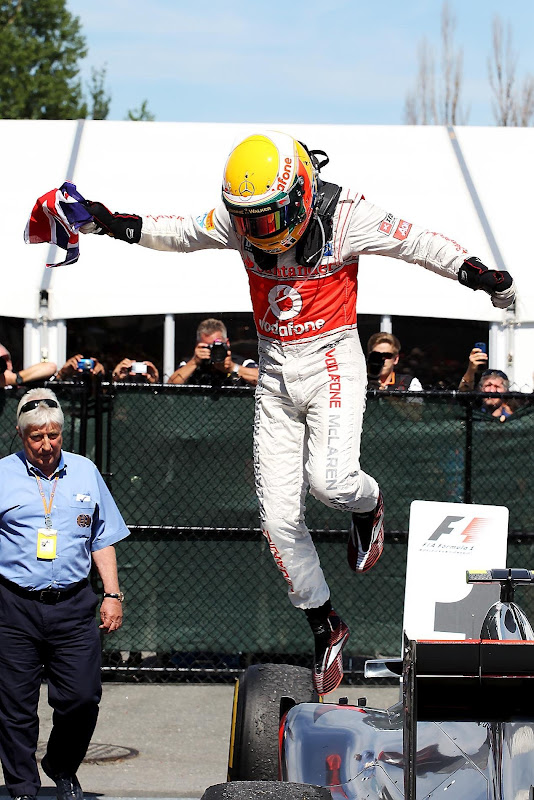 Льюис Хэмилтон выпрыгивает из своего McLaren с британским флагом в руке после победы на Гран-при Канады 2012