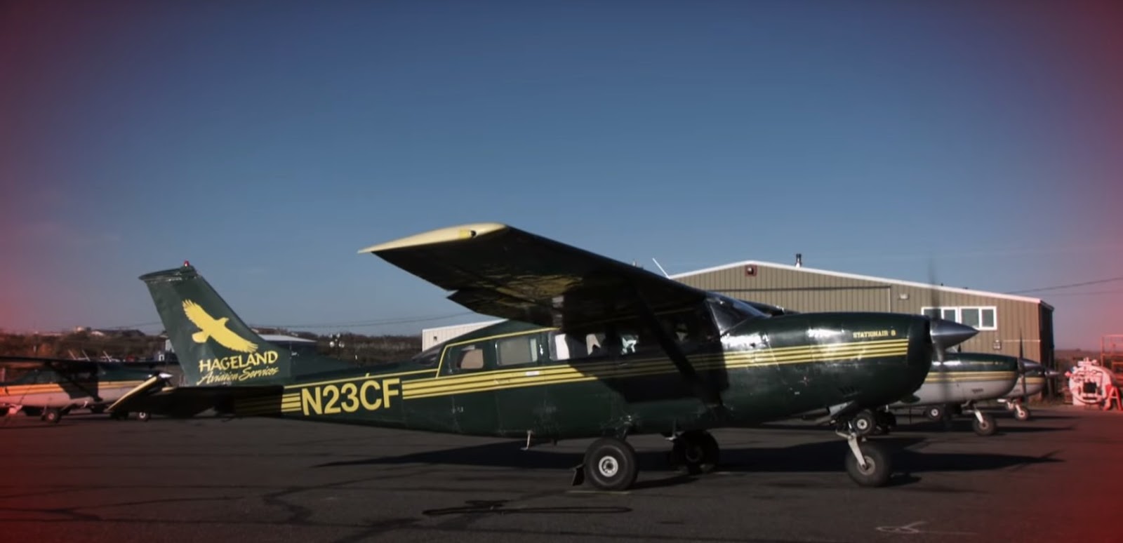a green Cessna 207 parked at the airport area
