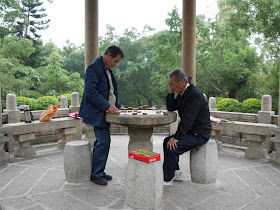 two men playing xiangqi (chinese chess) under a pagoda in Beishan Park, Yangjiang, China