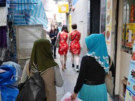 two women wearing hijabs and two other women in the distance wearing cheongsam (qipaos)