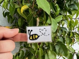 A hand holding a white sign in front of a green plant

Description automatically generated with low confidence