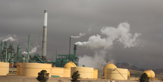 a factory somewhere in California, painted yellow and silhouetted against a stormy-gray sky