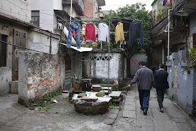 two men walking underneath hanging laundry in Guangzhou alley