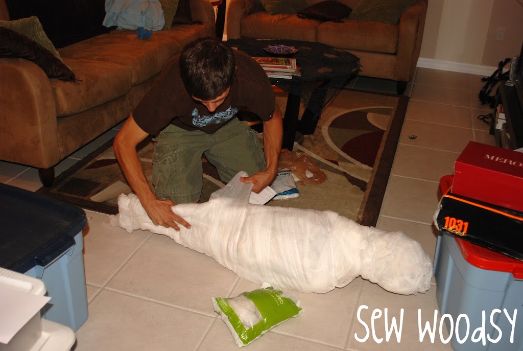 Man wrapping cheesecloth around a dummy.