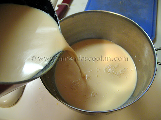 A photo of the combined ingredients for orange ice cream being poured into a stainless steel bowl.