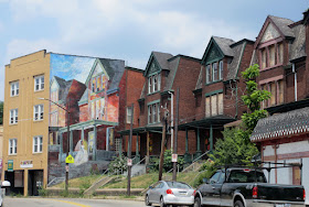 Wide angle view of the building with the mural on the left, and two of the original nine, identical houses to the right.