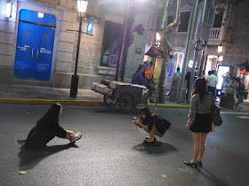young woman being photographed while sitting in the middle of a street at night
