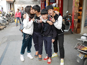 Two of four teenagers in Yangjiang, China, kiss while posing for a photo.