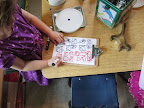 Child writes symbols on a small clipboard.