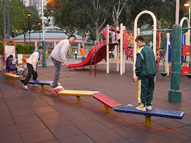 people playing on a row of wobbly connected planks at Fung Tak Park in Wong Tai Sin, Hong Kong