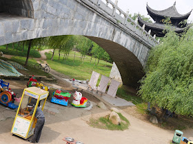 circular kiddie train and area for shooting balloons under a traditional Chinese style bridge