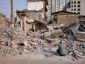 man squatting down in front of demolished buildings at Beizheng Street in Changsha