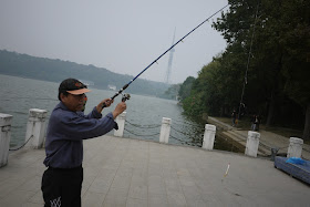 man wearing a baseball cap and holding a fishing rod in Changsha, China