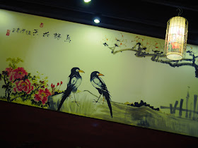 A wall at a restaurant in Hengyang with a classical Chinese style painting of a scene with two birds.