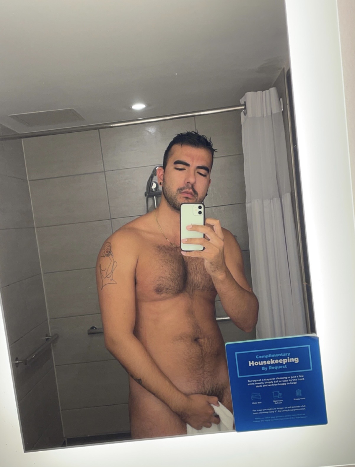 naked gay male onlyfans creator posing naked with a towel in an NYC hotel bathroom mirror selfie
