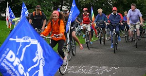 Radfahrerinnen mit blauen DFG-VK-Fahnen.