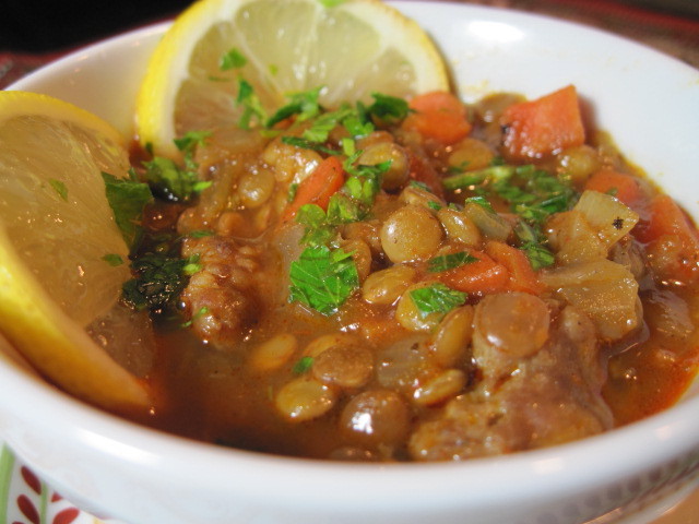 A white bowl filled with Lentil Stew with parsley and lemon.
