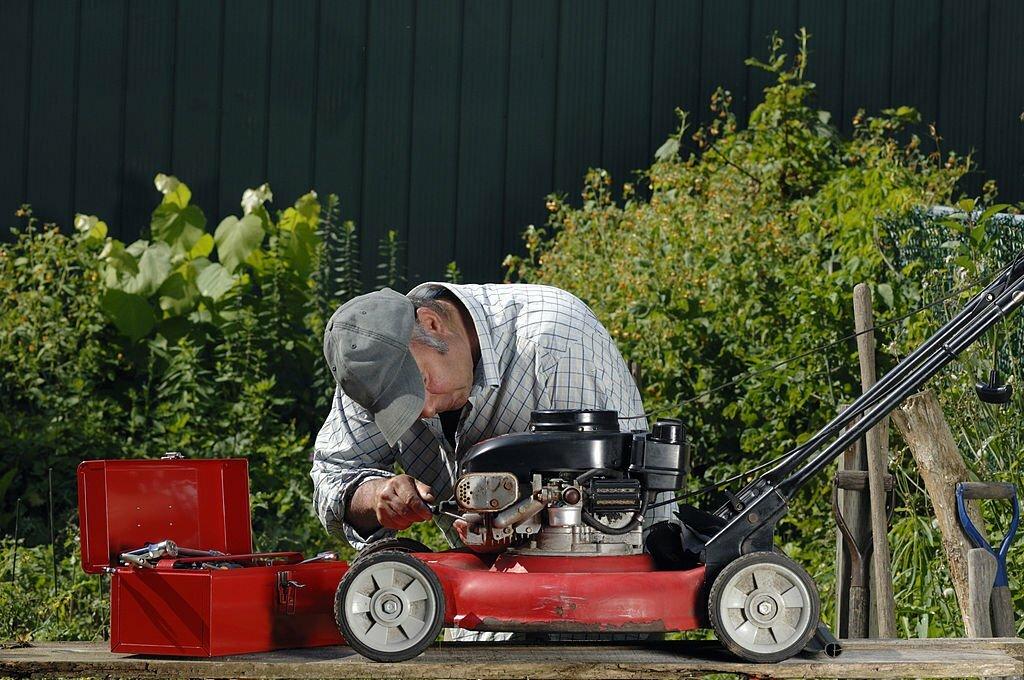 A person working on a lawnmower
Description automatically generated