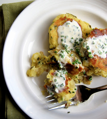 top down shot of garlic and chive potato cakes on a plate with creme fraiche