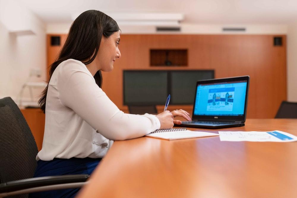 woman in white long sleeve shirt using black laptop computer