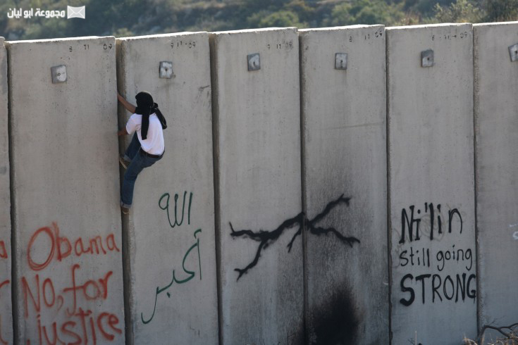شاب فلسطيني يتسلق جدار العنصرية