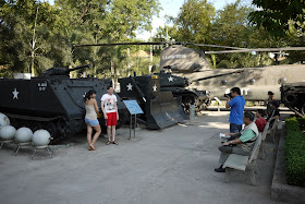 two young people being photographed in front of a U.S. tank