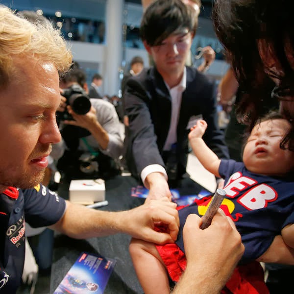 Red Bull Formula One driver Sebastian Vettel of Germany signs his autograph for a fan after speaking at an event at Nissan Motor Co's global headquarters in Yokohama, south of Tokyo.
