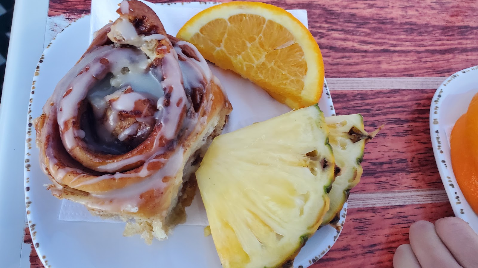 Image of a cinnamon roll, orange slices, and pineapple slices.