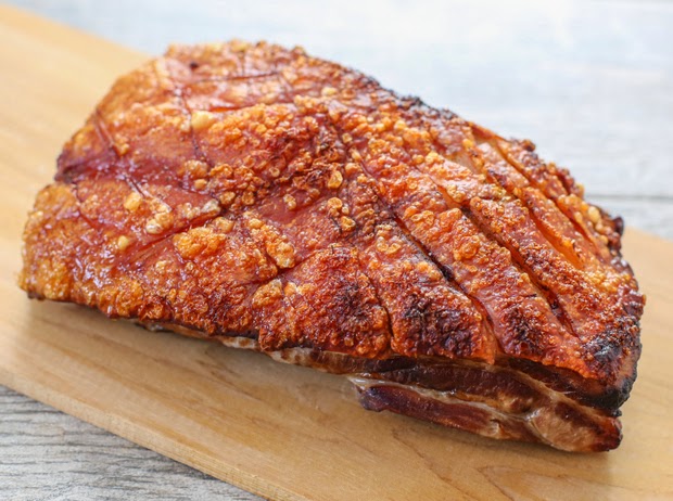a whole cooked pork belly with crunchy skin on a cutting board