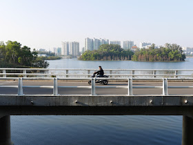 man on motorbike on bridge over Yuanyang Lake in Yangjiang, China
